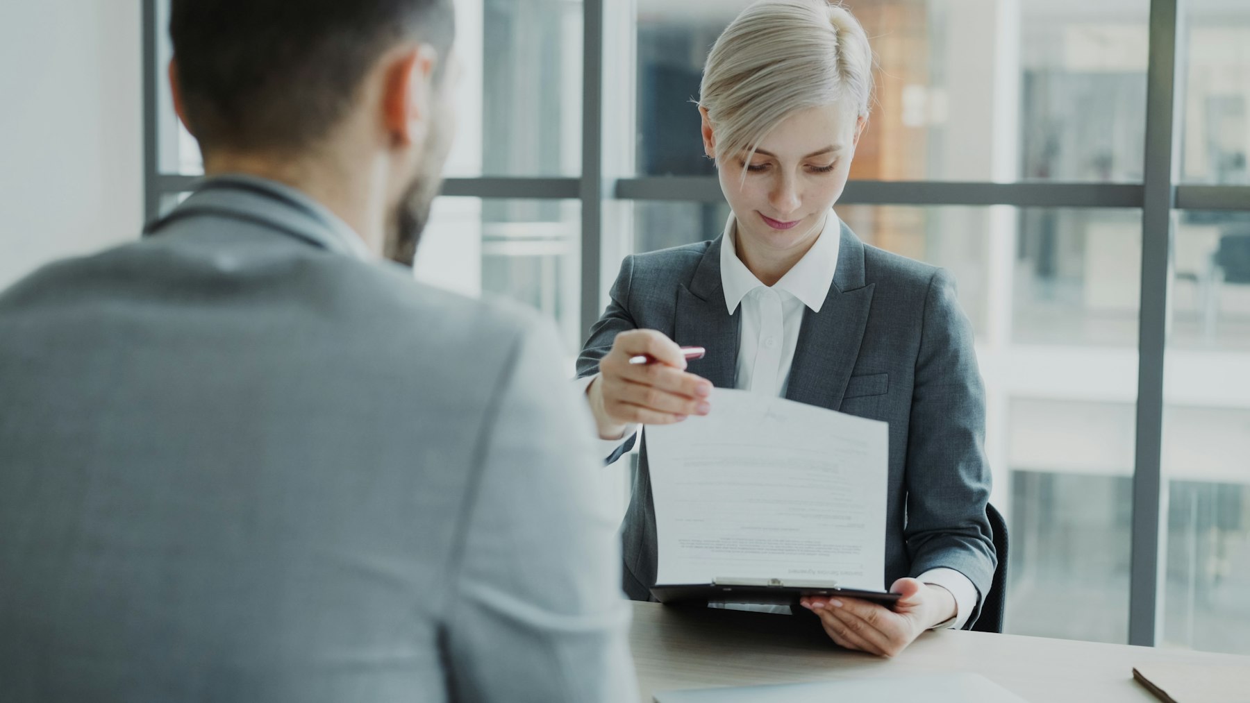 Consultora da Alpha Travel entregando documentos ao cliente durante entrevista de visto